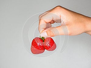 Female hand holding two strawberries