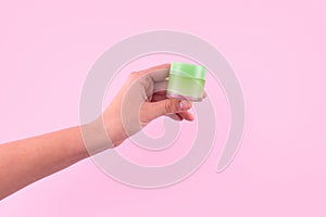 Female hand holding unbranded green plastic tube. Flacon for cream, toiletry. Bottle for professional cosmetics product. Skincare