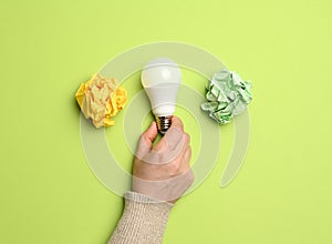 Female hand holding white glass lamp, green energy