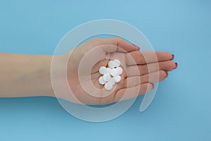 Female hand holding a white tablet on a blue background, concept of health