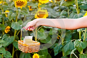 Female hand holding a wicker basket with a jug of sunflower oil