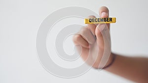 Female hand holding wooden block of calendar with month Desember