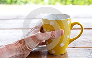 Female hand holding yellow polka dot mug
