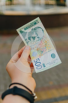 Female hand holds a banknote of 500 five hundred Serbian dinars on a street in the city