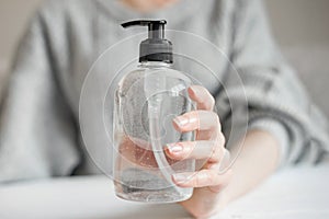 Female hand holds a bottle of a antibacterial gel  alcohol spray  liquid soap  antibacterial from coronavirus bacteria over light