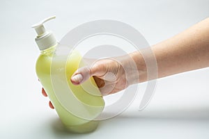 Female hand holds a bottle with liquid yellow antiseptic soap on a white background. Horizontal orientation
