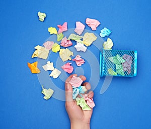 Female hand holds a bunch of crumpled multi-colored pieces of paper