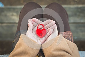 Female hand holds closed red padlock