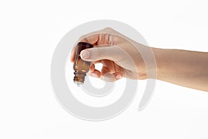 Female hand holds a glass bottle with a dropper on a white background, liquid, essence, oil, in a dark bottle, the concept of drug