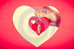 Female hand holds little heart with keys.