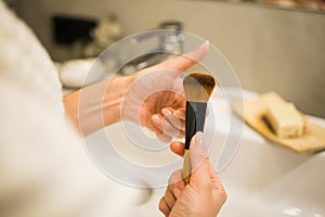 Female hand holds makeup brush in bathroom. Make-up artist profession concept. Variety of visagist tools glamor