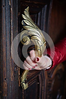 Female hand holds ornate brass door handle