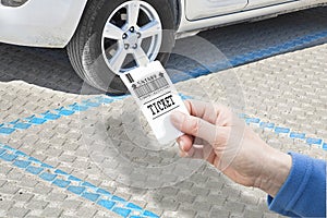 Female hand holds a parking ticket - parking payment concept with parked car