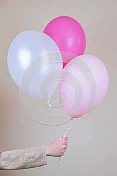 A female hand holds a pink helium balloon. The concept of holiday decorations, accessories for the children`s holiday