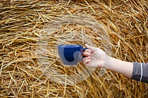 Female hand holds a porcelain cup of coffee on a natural background. Selective focus on the cup