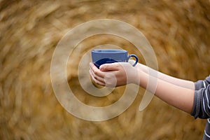 Female hand holds a porcelain cup of coffee on a natural background. Selective focus on the cup