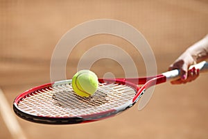 Female hand holds tennis racket with yellow ball
