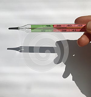 Female hand holds a thermometer. thermometer shows heat, high temperature