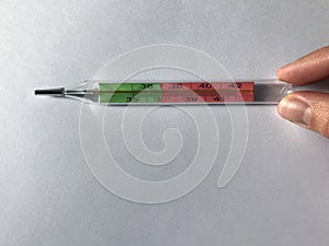 Female hand holds a thermometer. thermometer shows heat, high temperature