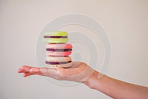 Female hand holds three multi-colored cookies macaroons on a white background