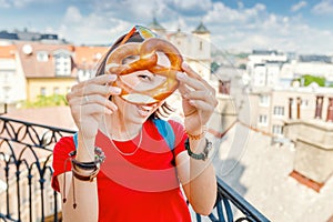 Female hand holds a traditional bakery and a pretzel delicacy against the background of the historic center of the European city