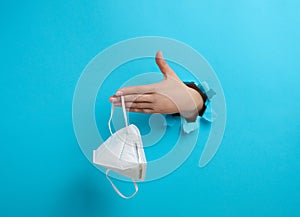 A female hand holds a white disposable medical mask to protect against viruses during an epidemic and pandemic. Part of the body