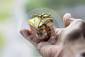 A female hand holds a yellow gift box with a bow