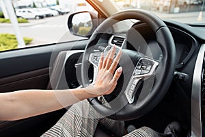 Female hand honking, beeping in a modern car photo
