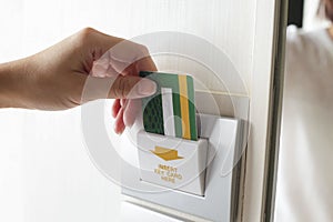 Female hand insert room card key to open electric light hotel room.