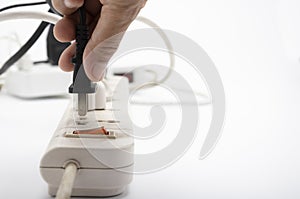 Female hand inserting a plugs into multi electrical power strip on white background , unsafety concept