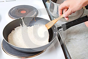 Female hand inverts pancake on a pan