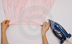 Female hand ironing clothes top view isolated on white background. Young woman with iron ironing man`s shirt seen from above