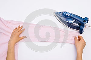 Female hand ironing clothes top view isolated on white background. Young woman with iron ironing man`s shirt seen from above