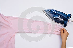 Female hand ironing clothes top view isolated on white background. Young woman with iron ironing man`s shirt seen from above