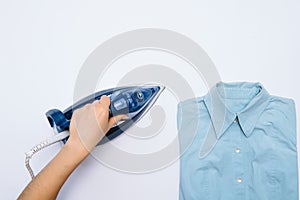 Female hand ironing clothes top view isolated on white background. Young woman with iron ironing man`s shirt seen from above