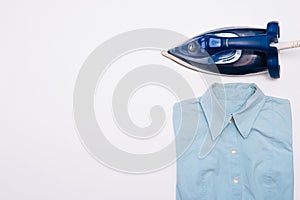 Female hand ironing clothes top view isolated on white background. Young woman with iron ironing man`s shirt seen from above