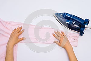 Female hand ironing clothes top view isolated on white background. Young woman with iron ironing mans shirt seen