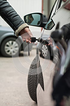 Female hand with key opens car door