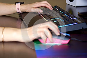 Female hand on the keyboard and gaming mouse. Gaming keyboard and mouse with colorful backlight