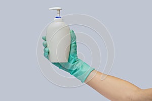 Female hand in latex rubber glove and hand sanitizer or liquid soap dispenser over light grey background