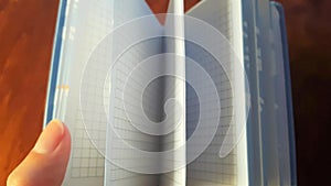 Female hand leaf through a small notebook, closeup view