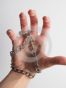 Female hand on a light background entwined with a chain