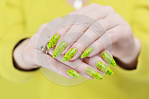 Female hand with long nails and a bright yellow green neon manicure