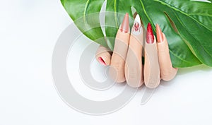 Female hand with long nails with glitter nail polish. Long red nail design with rhinestones. Women hand with sparkle manicure on