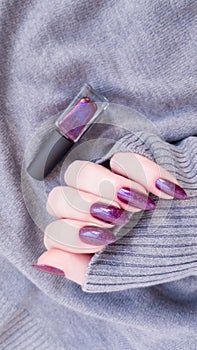 Female hand with long nails holds a bottle nail polish