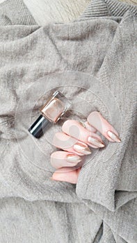 Female hand with long nails holds a bottle nail polish