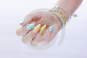Female hand with long nails and multi-colored bright bottle manicure with nail polish