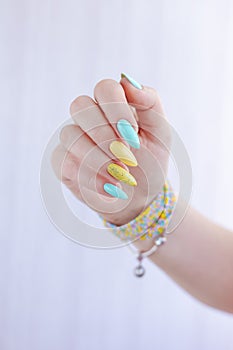Female hand with long nails and multi-colored bright bottle manicure with nail polish