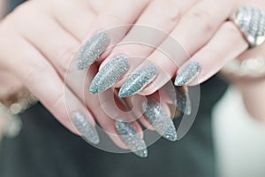 Female hand with long nails and a white gray silver manicure