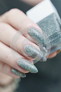 Female hand with long nails and a white gray silver manicure